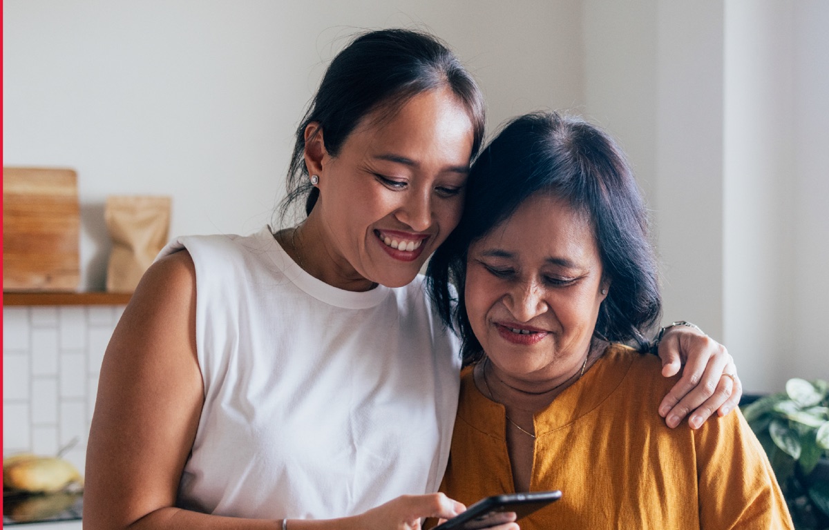 Deux femmes souriantes consultent ensemble un téléphone, visuel officiel British Council IELTS